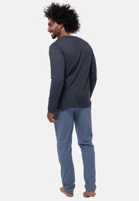 Langärmliges graues Baumwollhemd, kombiniert mit hellblauen gemusterten Schlafanzughosen, die einen lässigen Schnitt und ein einfaches Rundhalsdesign aufweisen.