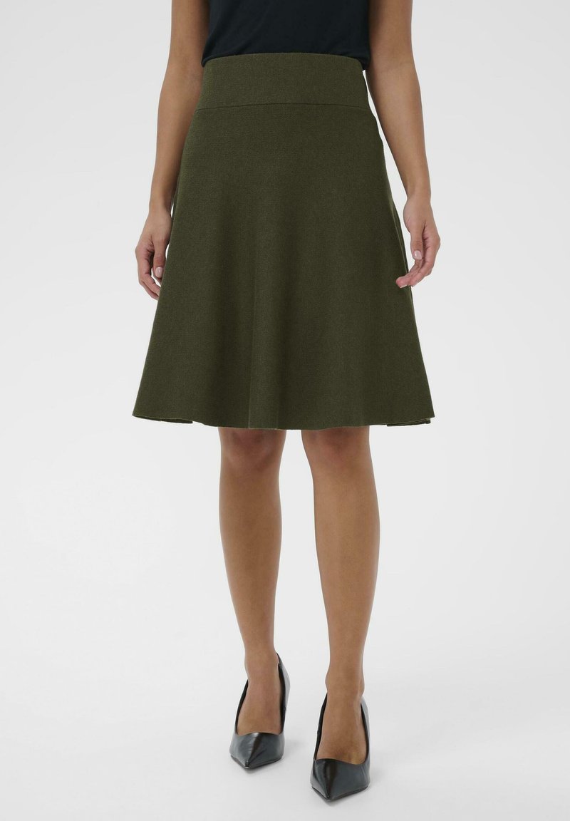 Gonna A-line verde oliva con vita aderente, realizzata in tessuto testurizzato, che si allarga delicatamente, arrivando a metà polpaccio. Indossata con tacchi neri a punta.