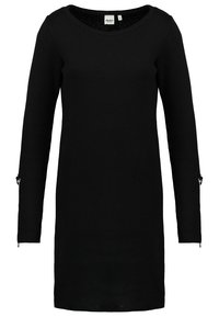 Abito lavorato a maglia nero con scollatura rotonda, maniche lunghe e cerniere laterali sui polsini. Presenta una linea dritta e un tessuto strutturato.