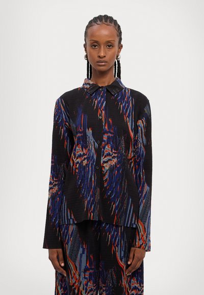 Fekete gombos ing színes, absztrakt mintázattal kék, piros és bézs színben. Állítható gallérral és hosszú ujjal rendelkezik. Texturált anyagból készült.