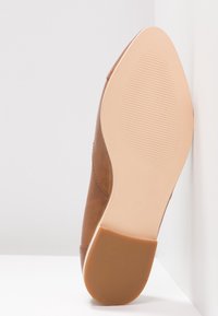 Semelle d'une chaussure en cuir marron avec une semelle extérieure beige lisse et un talon rectangulaire en caoutchouc, taille 37, reposant sur une surface blanche.