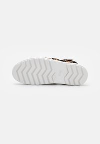 Tênis com parte superior em tecido estampado de leopardo preto e laranja, sola de borracha branca com padrão de ranhura em zigzag e logotipo no calcanhar.