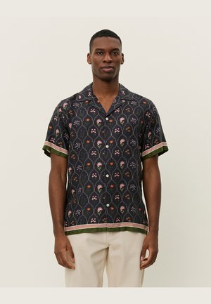 Short-sleeved shirt in dark fabric with floral pattern in pink, green, and orange. Features a contrasting green hem and striped accents.