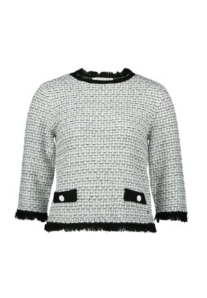 Witte en zwarte tweed top met driekwart mouwen, een rafelige halslijn en zoom, zwarte accentzakken met witte knopen.