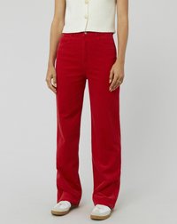 Pantalons en velours côtelé rouge à jambes larges avec deux poches avant et une fermeture éclair. Associés à un top court blanc et des baskets blanches.