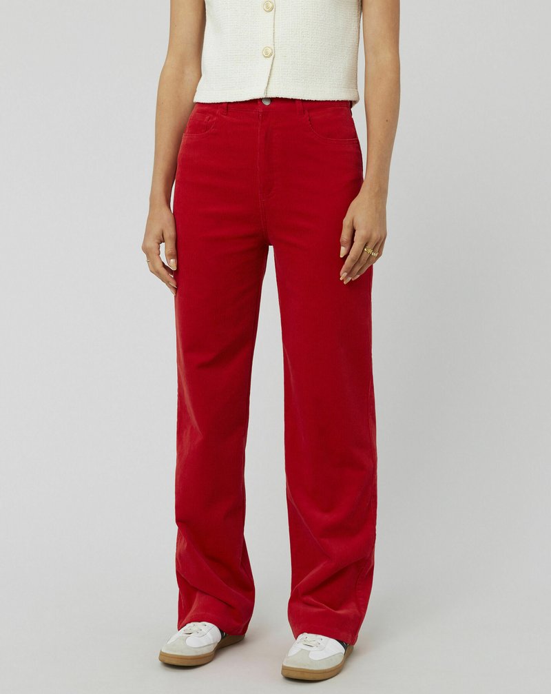 Pantalons en velours côtelé rouge à jambes larges avec deux poches avant et une fermeture éclair. Associés à un top court blanc et des baskets blanches.