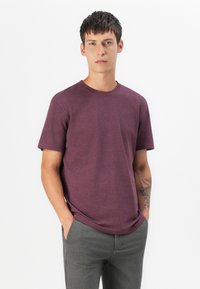 Kurze Ärmel, Rundhals-T-Shirt in einem kräftigen dunkelroten Farbton, aus strukturiertem Stoff, kombiniert mit grauen Hosen. Hat einen lockeren Schnitt.