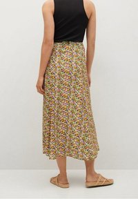Falda midi floral con un fondo beige, flores vibrantes en tonos rosa, verde y naranja, con una tela suelta y fluida y una cintura cómoda.