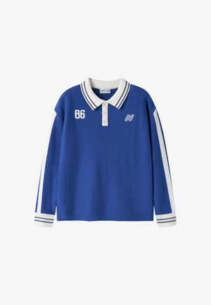 Polo bleu à manches longues avec col et poignets blancs, rayures blanches sur les manches, numéro 86 sur la poitrine gauche et logo blanc sur la poitrine droite.