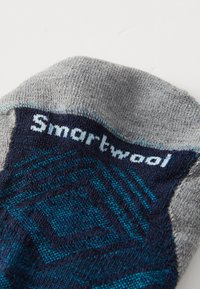 Kneelange sokker i grå, marineblå og teal. Har teksturerte mønstre og "Smartwool"-logo i hvitt. Laget av strikket stoff.