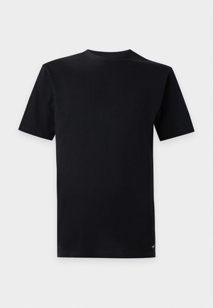 Camiseta negra lisa de manga corta con cuello redondo y un pequeño logo blanco cerca del dobladillo inferior sobre un fondo gris claro.