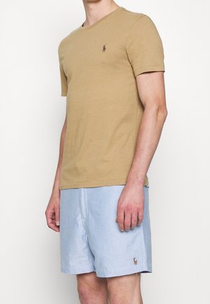 Tan cotton T-shirt with short sleeves and a small embroidered logo, paired with light blue shorts featuring a similar logo.