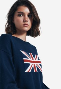 Maglione a maglia blu navy con design della Union Jack sulla parte frontale, con scollo rotondo e vestibilità rilassata. Morbido al tatto e con un motivo a punto medio.