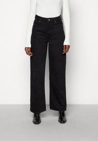 Svarta vida jeans med hög midja, med knappstängning fram och två sidofickor. Tyget har en slät, bomullstextur.