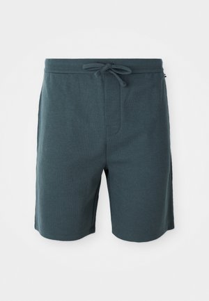 Calções masculinos em cor verde-escuro, feitos de um tecido texturizado. Apresentam uma cintura elástica com cordão e bolsos laterais.