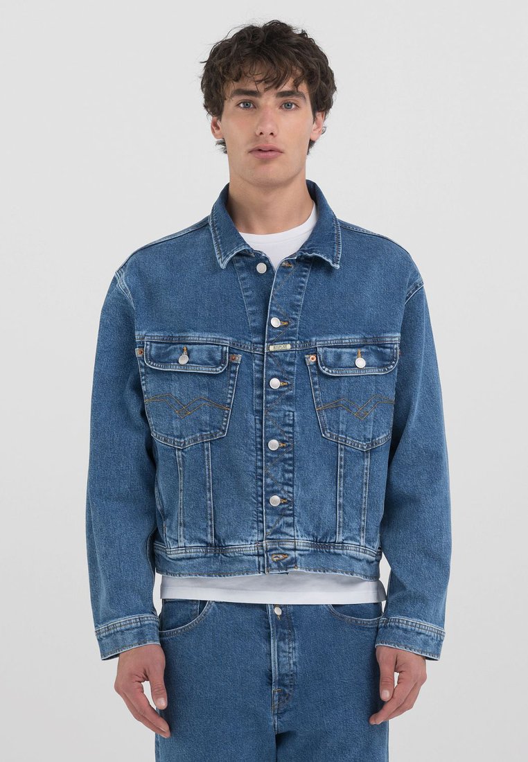 Jeans jakna v svetlo modri barvi s ovratnikom, gumbnim zapiranjem, dvema žepoma na prsih in kontrastnim šivanjem. Ima skrajšan dizajn in sproščen kroj.
