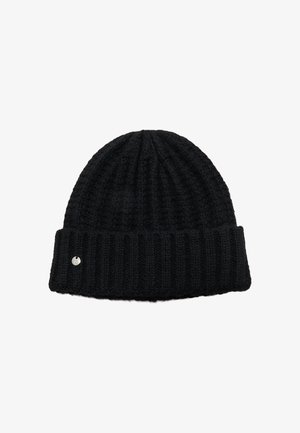Bonnet en tricot côtelé noir avec rebord replié et petit emblème rond argenté sur le rebord, isolé sur fond blanc.