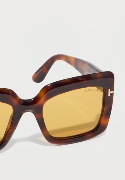 Ορθογώνια γυαλιά ηλίου σε σχέδιο χελώνας με κεχριμπαρένιους φακούς, παχύ πλαίσιο και το λογότυπο "Tom Ford" στον πάνω δεξιό φακό και στο βραχίονα του σκελετού.