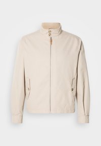 Μπεζ βαμβακερό μπουφάν με κοντό όρθιο γιακά, εμπρόσθιο φερμουάρ, δύο πλαϊνές τσέπες και διακοσμητικά κουμπιά. Ομαλή υφή με μινιμαλιστικό σχέδιο.