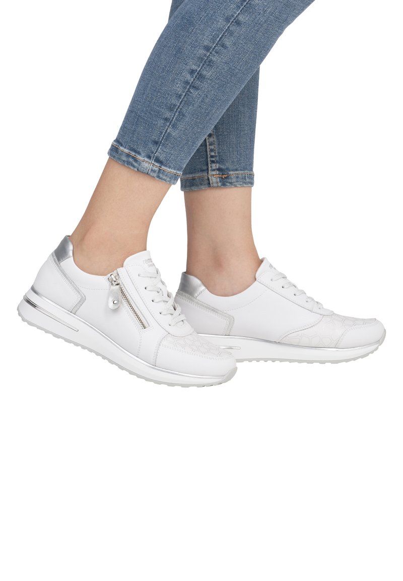 Baskets blanches avec un motif texturé, des accents métalliques et un détail zippé. Présente une semelle rembourrée et un design profil bas.