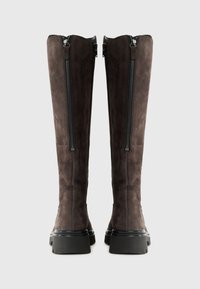 Bottes en daim marron jusqu'au genou avec des doubles fermetures éclair sur les côtés, bout carré et semelles en caoutchouc noir chunky. Texture lisse avec des détails de design minimalistes.
