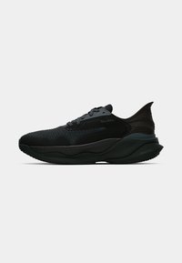 Baskets de sport noires basses avec dessus en maille texturée, fermeture à lacets, talon rembourré et semelle épaisse et amortissante, vues de profil sur fond blanc.