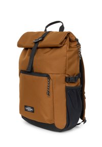 Mochila con cierre enrollable en tela marrón con detalles en negro, cuenta con correas ajustables, bolsillo lateral y cierre superior con hebilla.