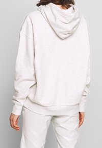 Hellgrauer Kapuzenpullover aus weichem Material mit entspanntem Schnitt, angesetzten Schultern sowie gerippten Bündchen und Saum.