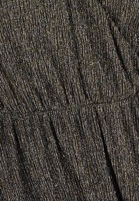 Tessuto nero strutturato con sottili fili d'oro e d'argento disposti verticalmente. Presenta dettagli arricciati che creano increspature e un aspetto a strati.