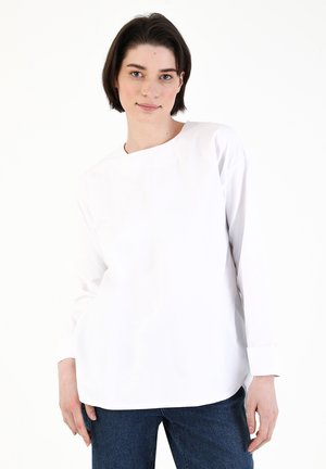 White long-sleeve shirt with a round neck, straight fit, and cuffs at the wrist. Made of smooth fabric, featuring a minimalistic design.