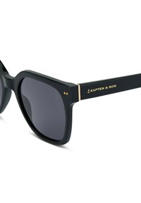 Černé sluneční brýle s matným povrchem, čtvercovým tvarem, tmavými skly a zlatými akcenty, na který jsou na stranicích umístěny logo značky "KAPTEN & SON".