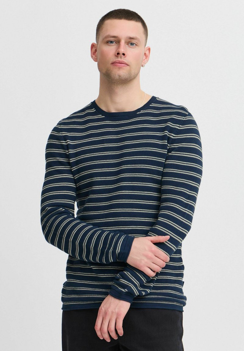 Camicia a maniche lunghe blu navy con righe verticali crema. Realizzata in tessuto liscio, presenta un colletto rotondo e un design aderente.