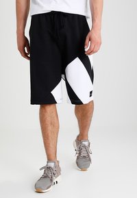 Black and white sports shorts with a geometric design, made of soft material. Features an elastic waistband and side pockets.