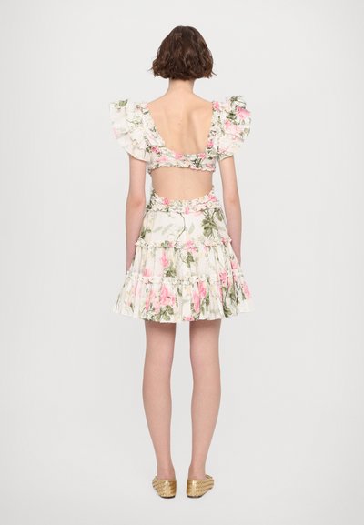Bloemrijke jurk met rimpels aan de mouwen en een uitsnede op de rug. Heeft een witte stof met roze rozen en groene bladeren, een gelaagde rok en gouden flats.