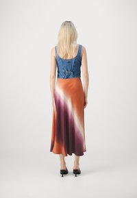 Denim crop top dengan desain pas yang bertransisi menjadi gaun panjang yang halus dengan efek ombre dalam nuansa oranye, ungu, dan putih.