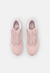 Helle rosa Sportschuhe mit einem strukturierten Mesh-Obermaterial, weißen Schnürsenkeln und einer gepolsterten Sohle. Verfügt über ein dezentes Logo an der Seite.