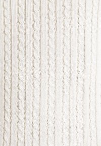 Kabelstickad tröja i off-white, med strukturerade vertikala ränder och vävt mönster. Mjukt material med ett bekvämt utseende.