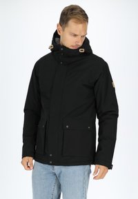 Black waterproof jacket with a high collar, two front pockets, snap buttons, adjustable hood, and soft inner lining for warmth.