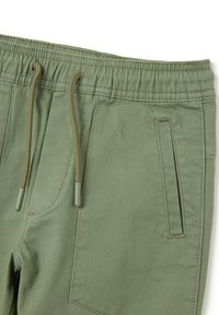 Grüne Baumwoll-Jogginghosen mit elastischem Bund und Kordelzug sowie einer Seitentasche. Weicher Stoff mit matter Oberfläche.