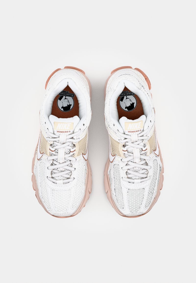 Nike Vomero 5 sneakers in wit mesh met lichtroze accenten. Voorzien van een gevoerde kraag, een gestructureerd ontwerp en grijze veters. Ronde neusvorm.