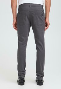 Grijze broeken van een katoenmix, met twee achterzakken, een slim fit ontwerp en een subtiele textuur. Gecombineerd met zwarte schoenen.