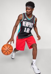 Tricou de baschet negru cu accente turcoaz, având inscripția "MEMPHIS" în litere albe și numărul 12, combinat cu pantaloni scurți roșii și adidași albi.