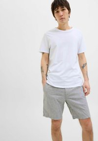 White cotton t-shirt with a crew neck paired with light grey linen shorts featuring a relaxed fit and side pockets.