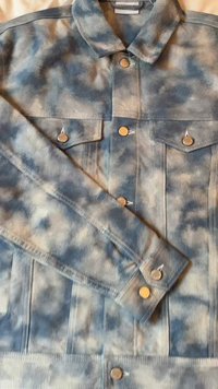 Denim striukė mėlynos ir šviesiai pilkos tvidinės spalvos. Pasižymi apykakle, dviem krūtinės kišenėmis ir metaliniais mygtukais. Tekstūruotas audinys.