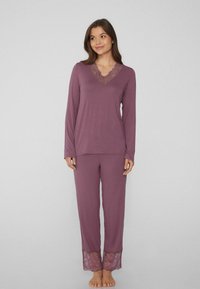 Zestaw odzieży loungewear w stonowanym mauve, składający się z długiego rękawa bluzki z koronkowym wykończeniem przy dekolcie oraz spodni piżamowych z koronkowymi akcentami na dole.