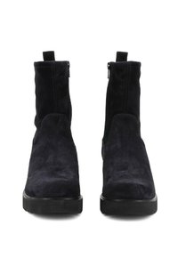 Stivaletti neri in suede con una texture liscia, punta rotonda, pannelli laterali elastici e una suola nera resistente. Dettaglio della cerniera sul retro.