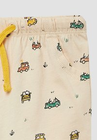 Beige shorts met een gele koord, voorzien van een patroon van kleurrijke cartoonauto's en kleine grasaccenten. Gemaakt van zacht katoen.