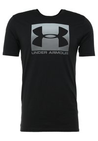 Camiseta negra de manga corta con un cuello redondo. Presenta un gran logo gris de Under Armour en el centro. Está fabricada con un material suave y elástico.