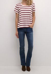 Stribet t-shirt i creme og maroon, korte ærmer, rund halsudskæring, parret med blå lige ben jeans og brune ankelstøvler.