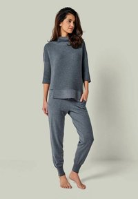 Graues gestricktes Loungewear-Set mit einem kurzärmeligen Rollkragenoberteil mit geripptem Design und passenden Jogginghosen mit schmal zulaufenden Bündchen.